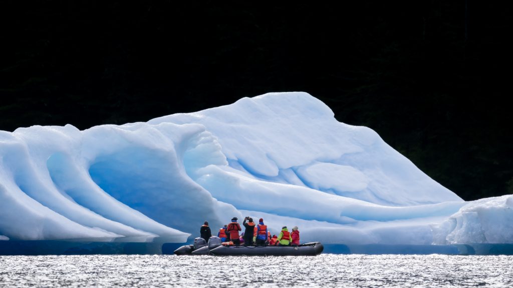 Tourists view a blue iceberg up close from a Zodiac